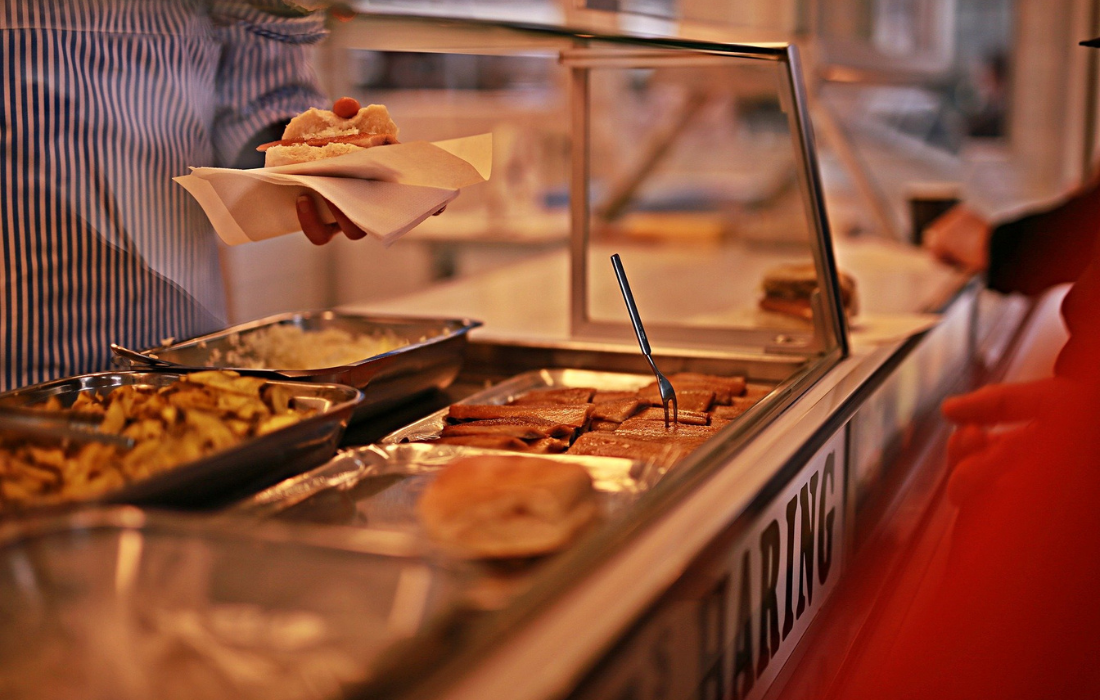 Un comptoir présentant différents aliments dans des bacs, dont des saucisses.